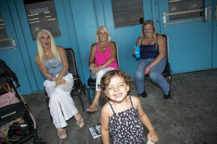 Women react and a toddler smiles.