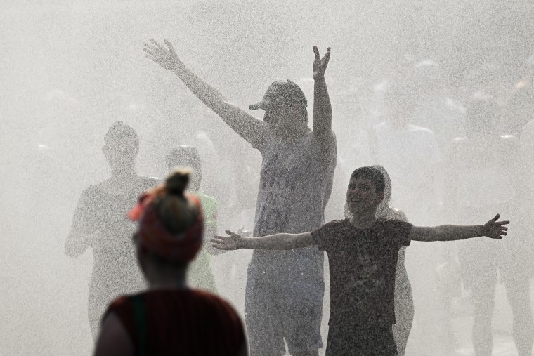 People with outstretched arms in a mist during a hot day.