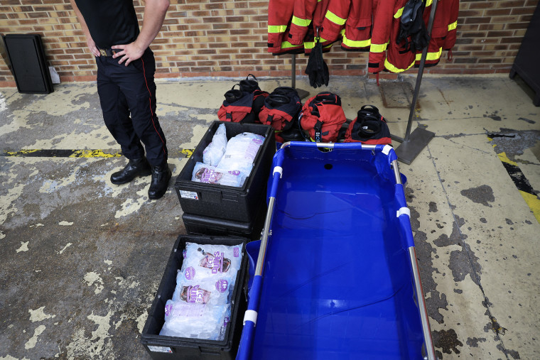 A firefighter seen from the waist down standing next to an emergency ice bath. 