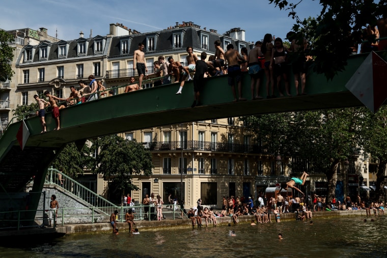 Young people jump and swim in the Canal Saint-Martin during a red alert heatwave in Paris on June 25.Gauthier Bedrignans / Hans Lucas/AFP via Getty Images