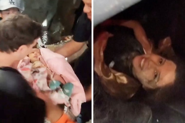 Rescuers pull a baby from the rubble of a collapsed building following deadly earthquakes that struck Venezuela on June 24, in La Guaira