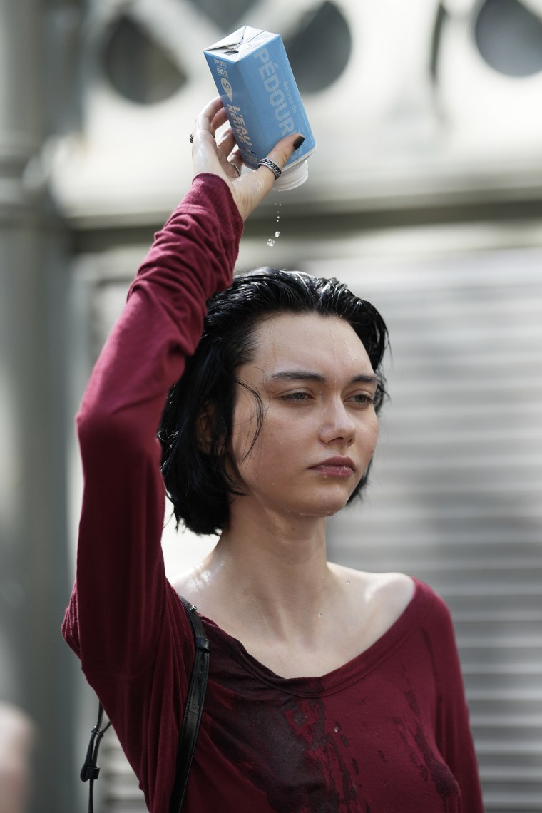 Une femme se verse une bouteille d’eau sur la tête.