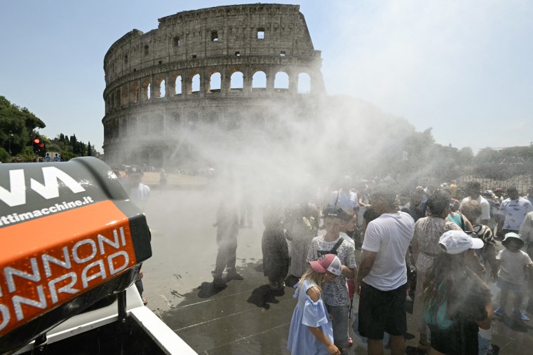 Un éventail souffle du brouillard sur les touristes rassemblés devant le Colisée à Rome.