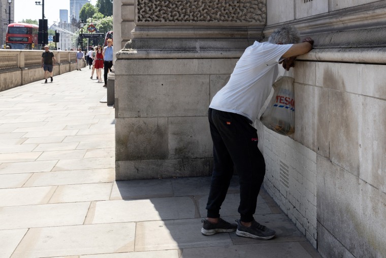Un homme posant sa tête sur une marche en béton dans l'ombre.