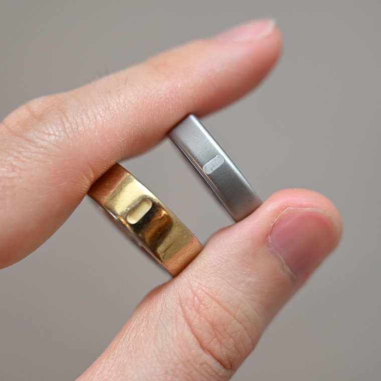 A close up of the Oura Ring 5 and Oura Ring 4 in a person’s hand.