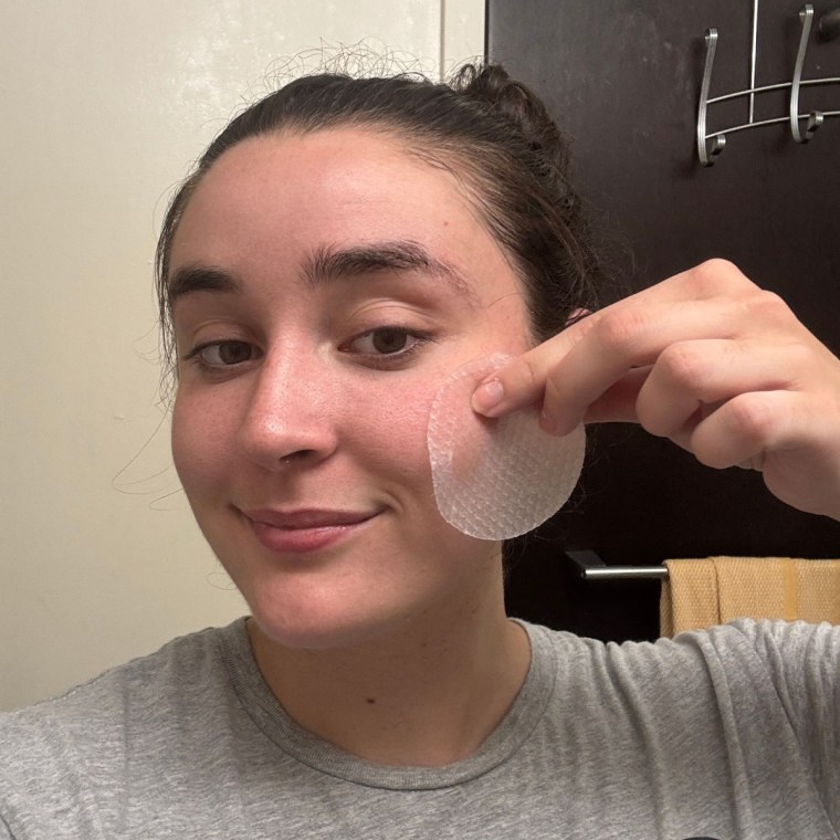 Woman applying toner pad to face