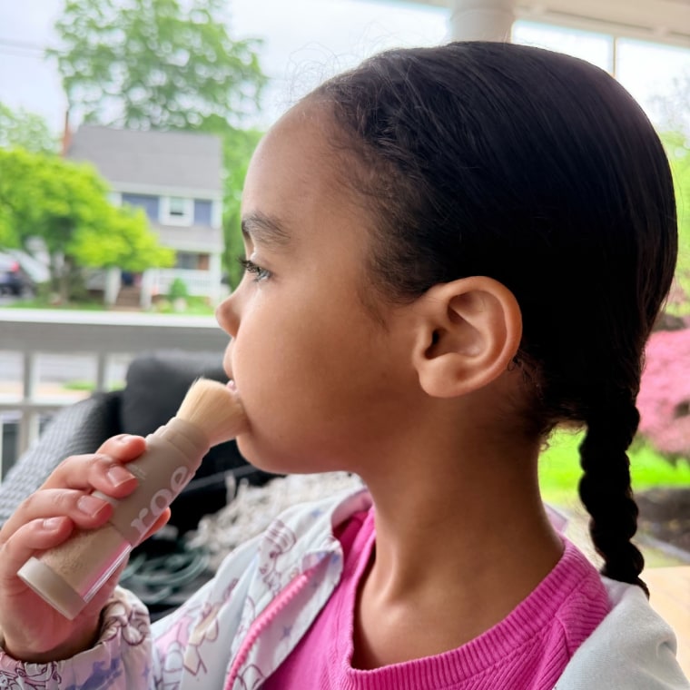 Child applying sunscreen powder on face
