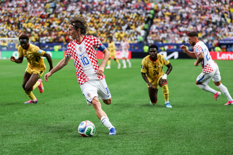 Luka Modric runs with the soccer ball, players run behind him on the field