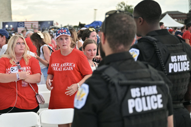 Two US Park police officers face toward three women, two of them wearing MAKE AMERICA GREAT AGAIN t-shirts.