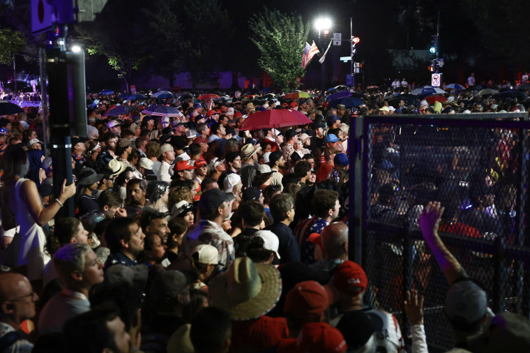 A throng of people moving through a street at night.