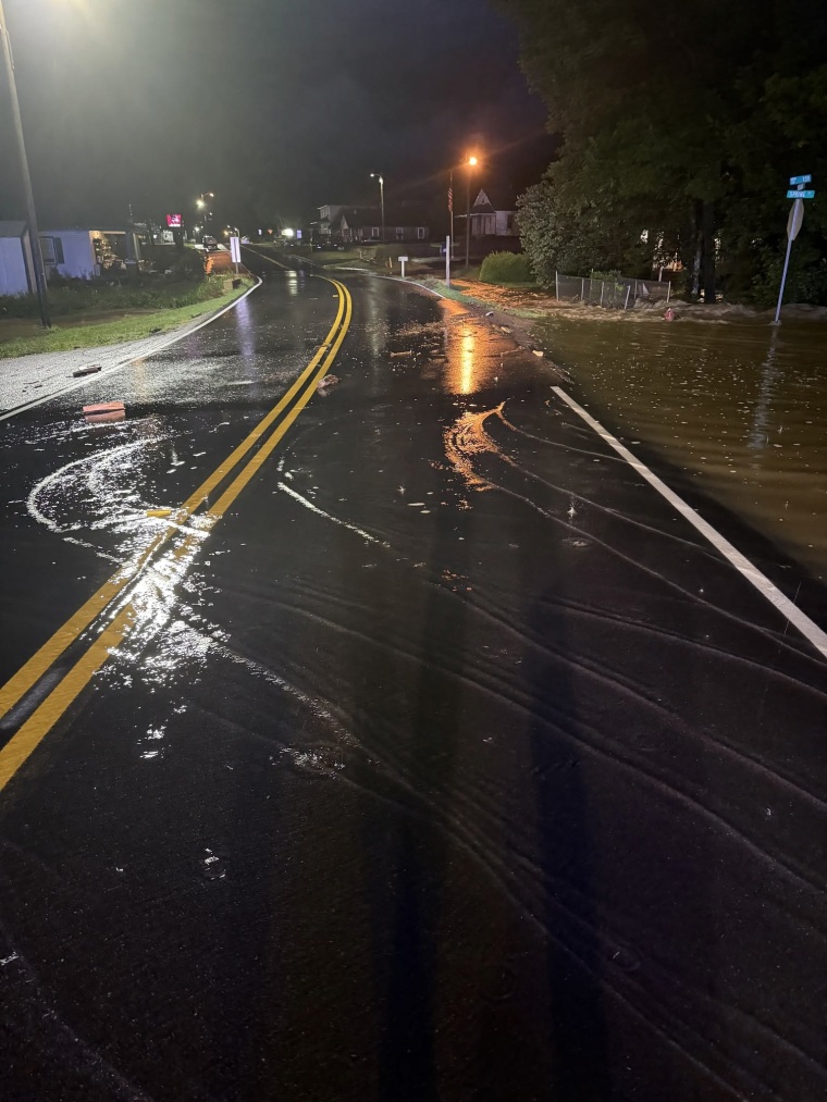 A flooded city street at night, illuminated by streetlights.