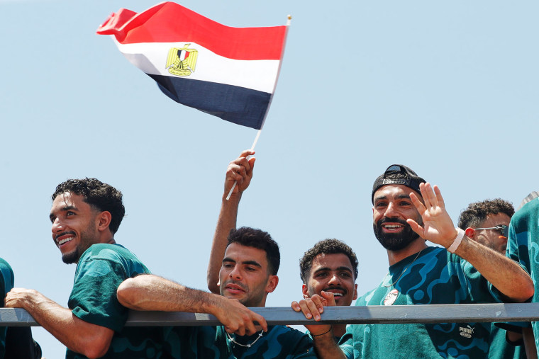Mohamed Salah, right, smiles as he is greeted by fans upon the Egyptian national soccer team's arrival at El-Alamein airport on July 10, 2026.