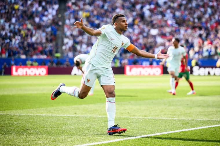 Kylian Mbappe runs on the soccer field with his arms outstretched