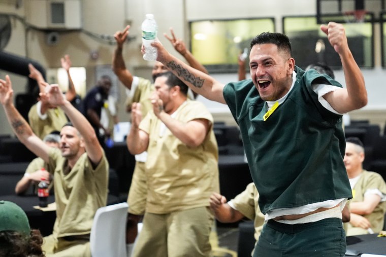 Victor Caldas cheers while inside of a prison amongst other inmates