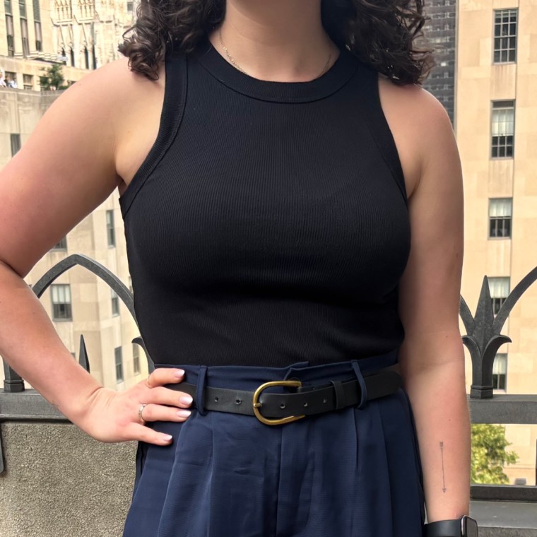 A woman standing outside and wearing a black tank top.