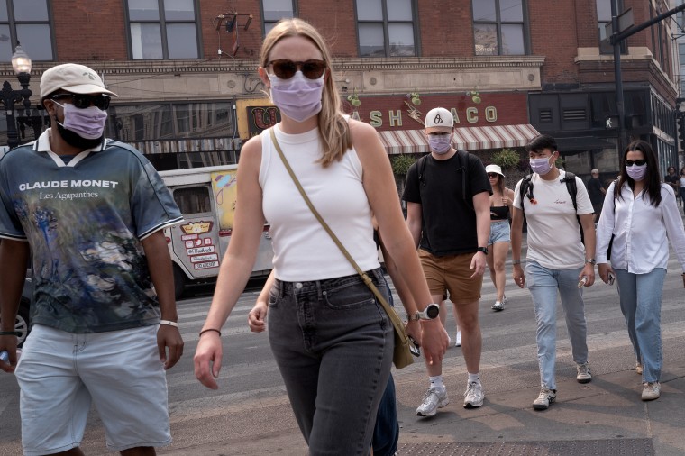 Five people wearing masks crossing an intersection in Chicago.
