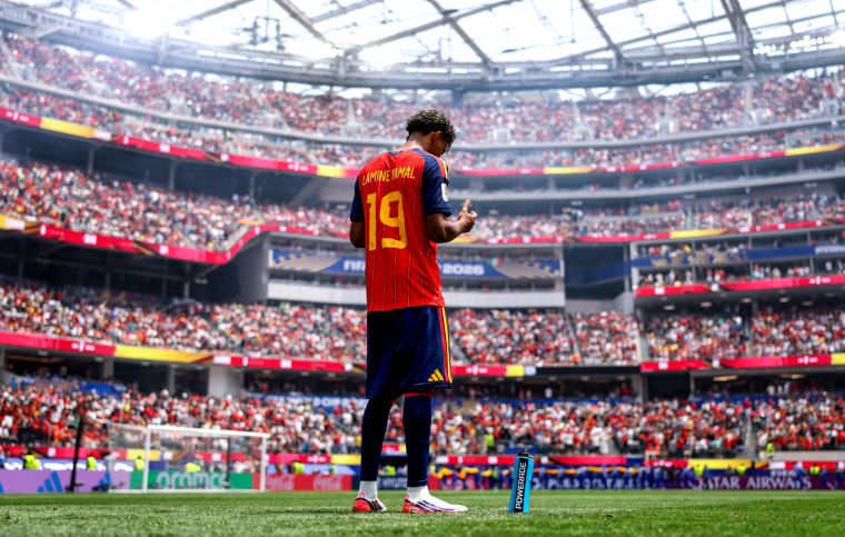 Lamine Yamal, back to camera, stands and prays on the soccer field