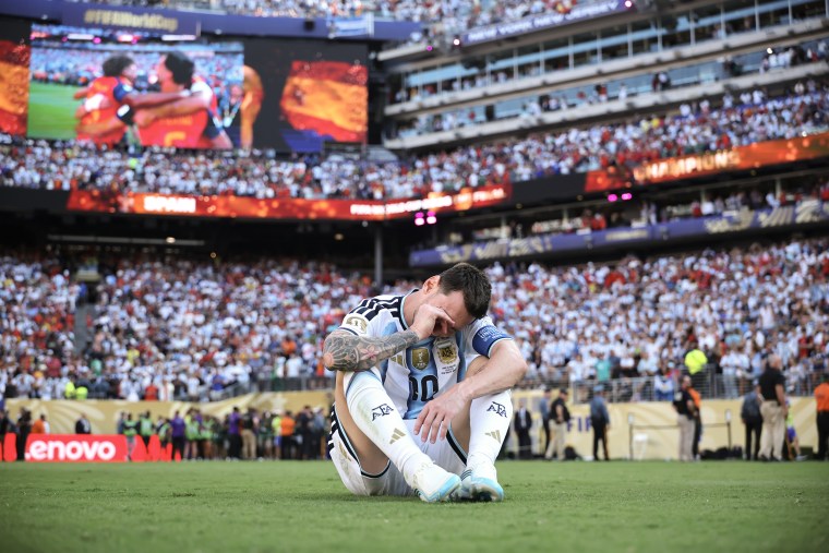 Lionel Messi sitting on the pitch after losing the world cup final match.