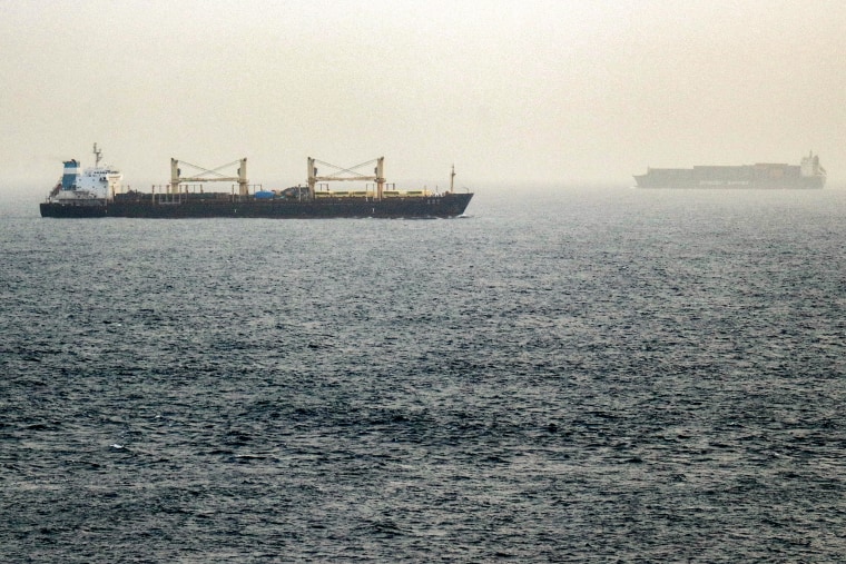 Two commercial tankers float in the distance in foggy, hazy weather.