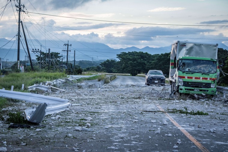 A damaged truck and car are seen on a debris-covered road following an explosion at the Aeon Mall Kumamoto in Kashima, Kumamoto Prefecture.