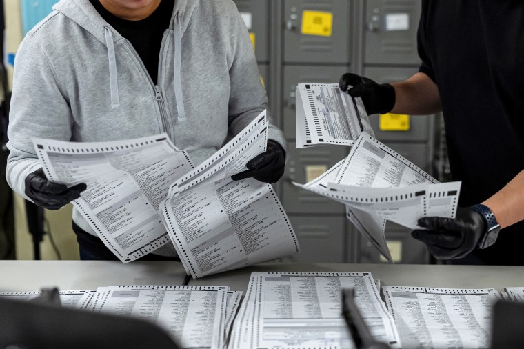 Election workers process mail-in ballots.