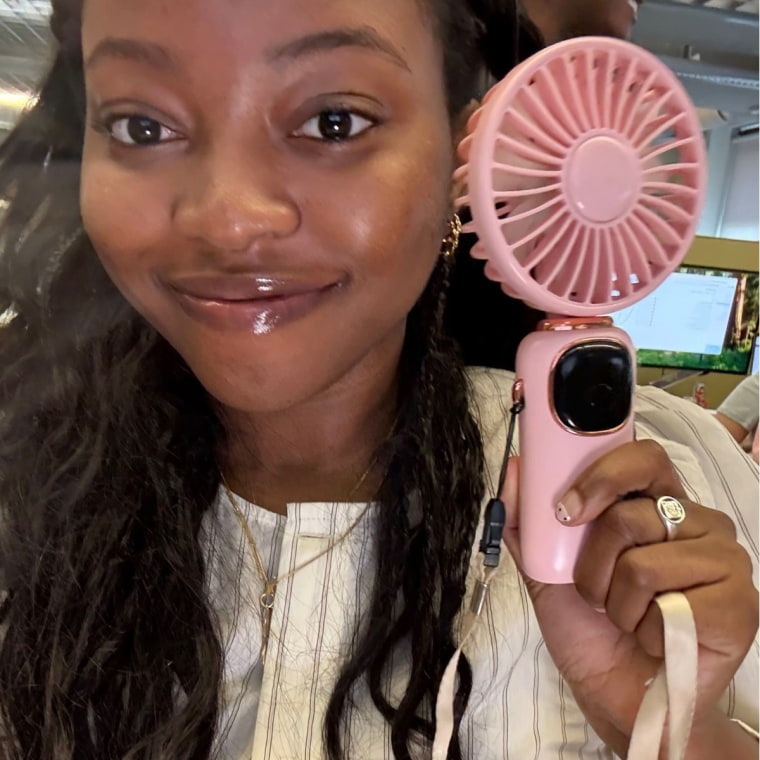 Woman holding pink handheld fan.