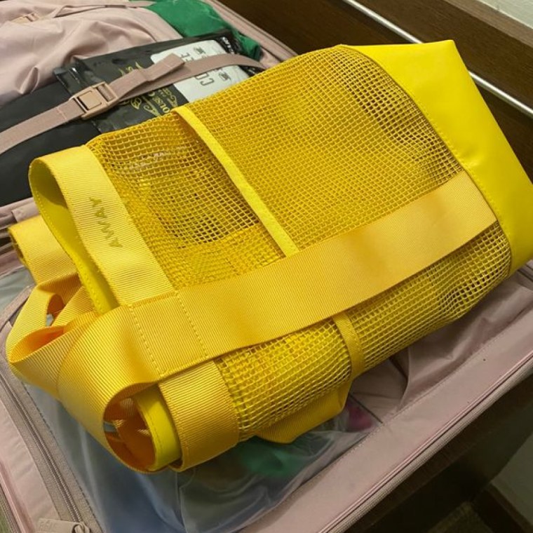 Yellow Away bag sitting inside a packed suitcase