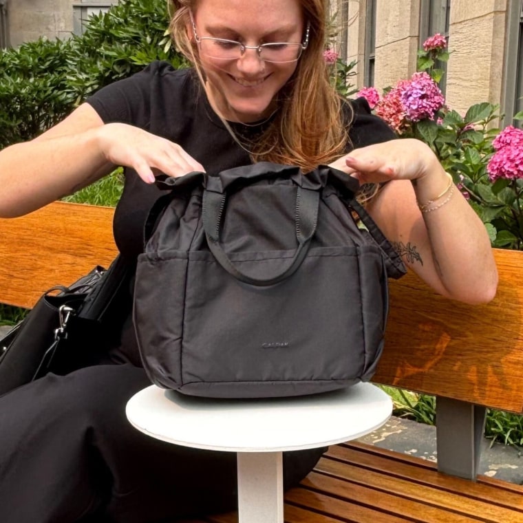 Γυναίκα κάθεται με Calpak Insolated Lunch Bag δίπλα της.