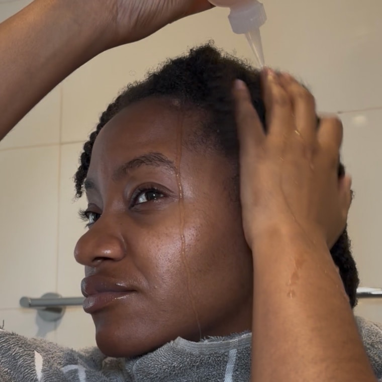 Morris applying the Cecred Fermented Rice & Rose Protein Ritual to her hair using a dropper bottle.