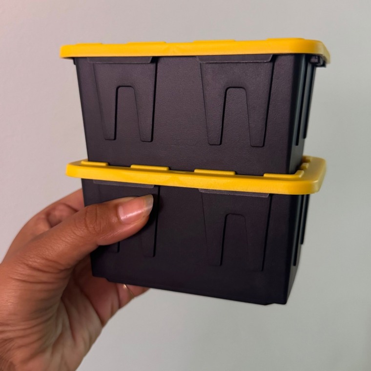 Person holding miniature storage bins stacked on top of each other.