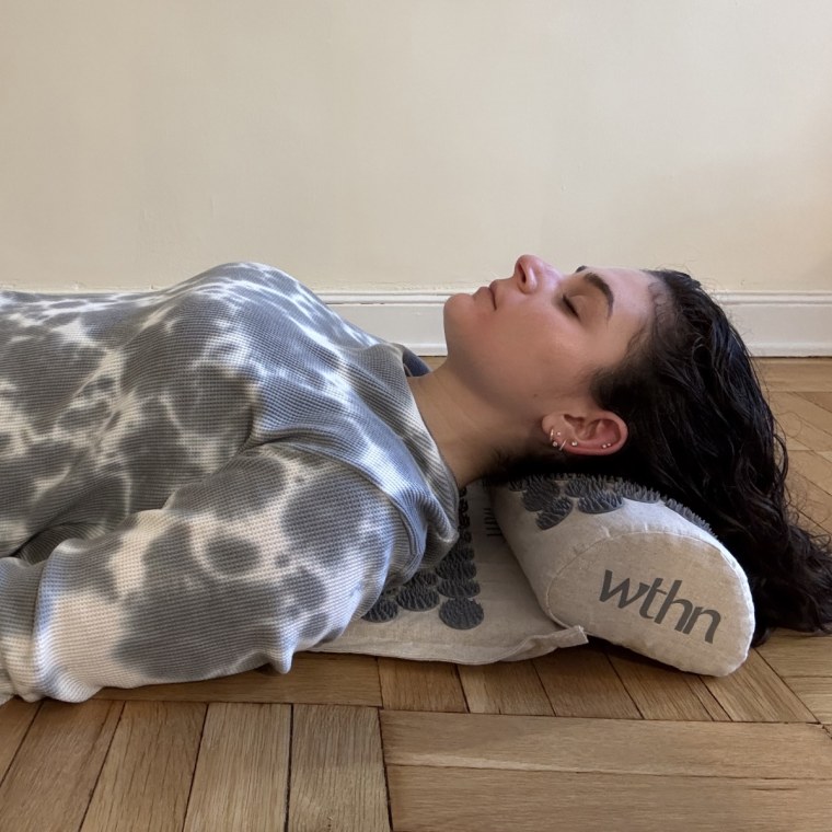 A woman laying on Wthn’s Acupressure Mat Set.