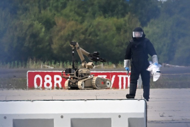 A forensic technician works alongside a bomb-disposal robot at Leipzig/Halle Airport in Germany.