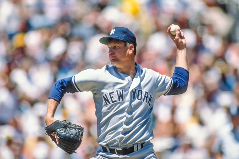 Tommy John throws a baseball on the field