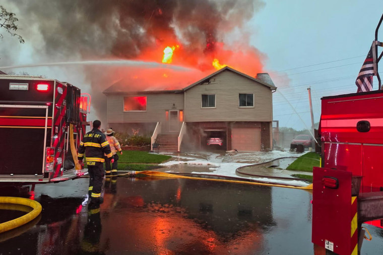House on flames as Fire Department attempts to control the fire with water hoses.