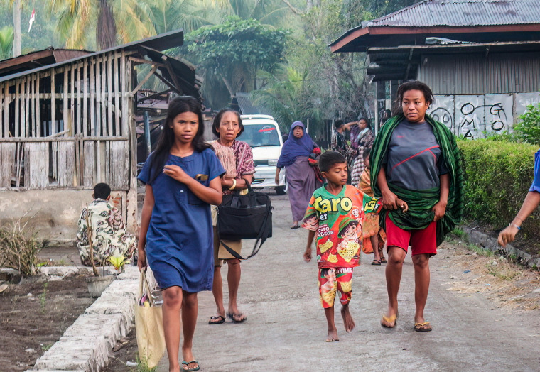 Villagers walk in the middle of the street.