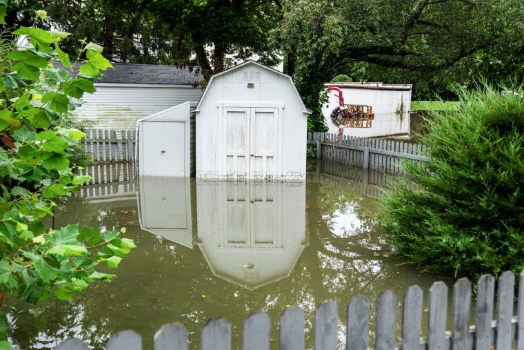 A shed in a backyard is seen submerged in flood waters