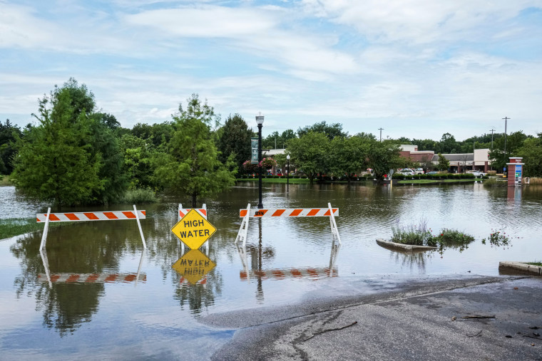 Floodwater sits on a road behind a "high water" caution sign