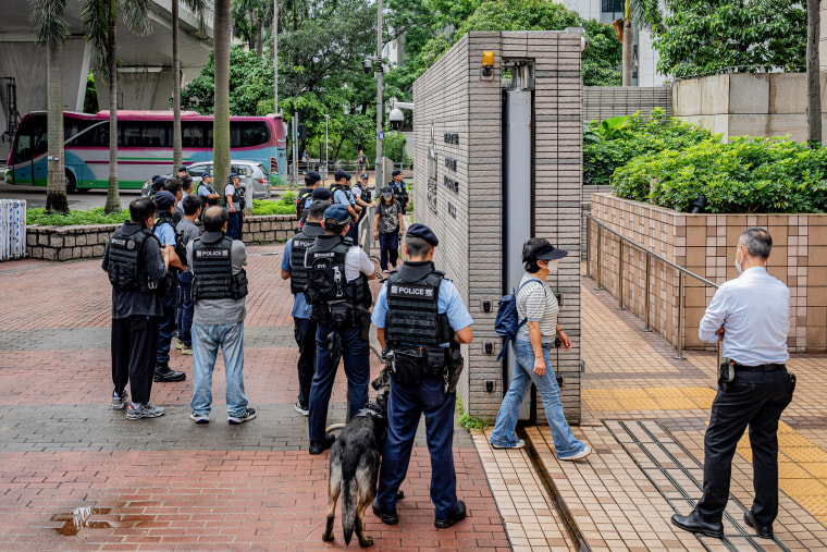 Police officers stand as people enter the West Kowloon Magistrates' Courts.