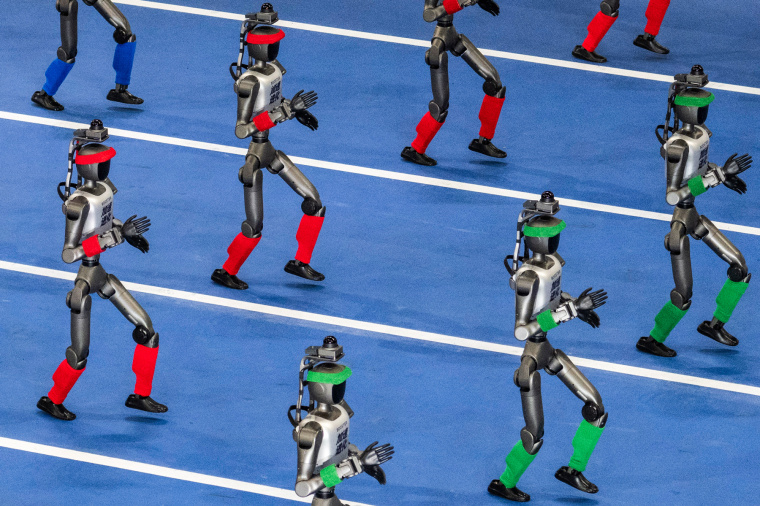 Humanoid robots walk in procession on a blue track