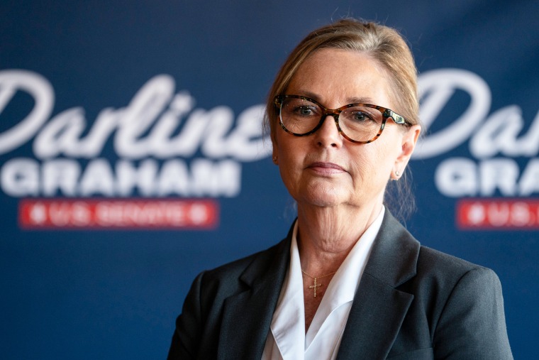 Darline Graham stands in front of a blue backdrop that reads