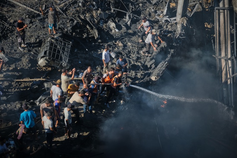 People try to extinguish a fire after an airstrike hit a building. 