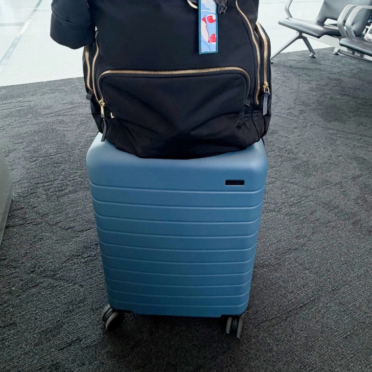 Away bigger carry-on in blue with Tumi backpack on top.