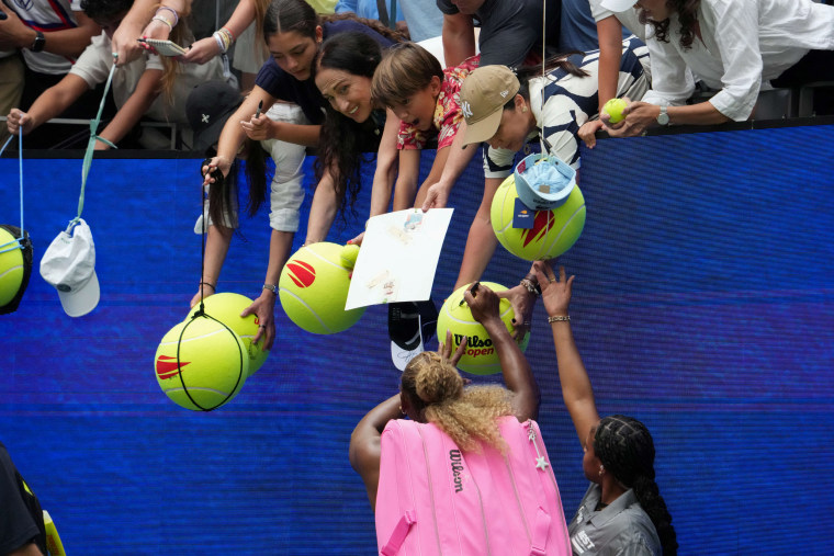 Fans leaning towards Serena Williams for autographs.
