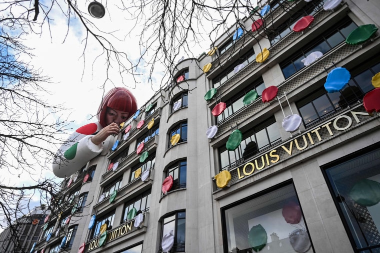 A large Yayoi Kusama appears over a Louis Vuitton boutique.