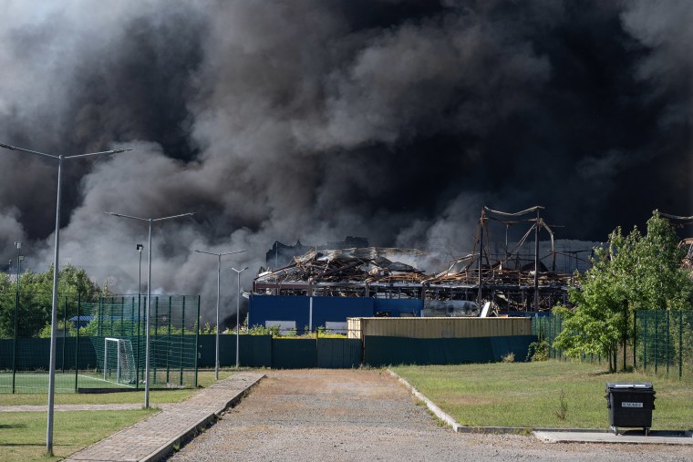Thick black smoke rising from a warehouse following a bombing attack.