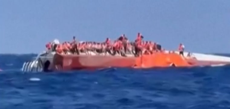 Passengers stand on a capsized ship off northern Cyprus as they await rescue Sunday.