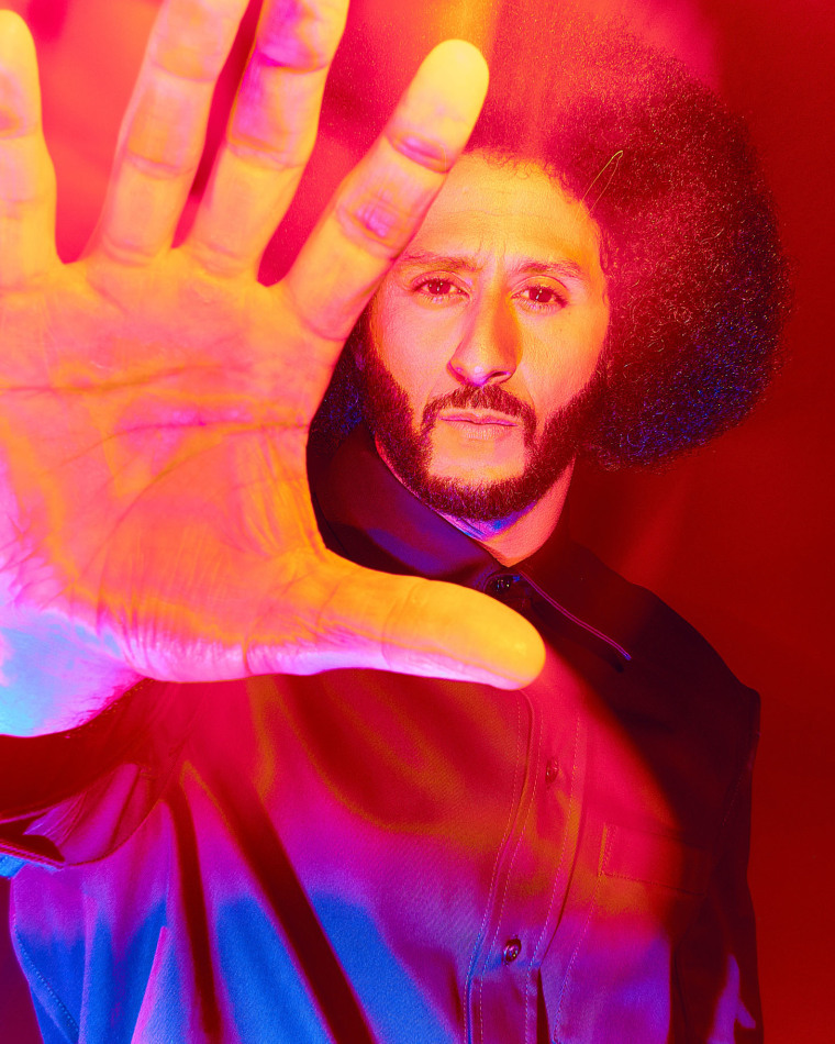 Colin Kaepernick holds his hand toward the camera