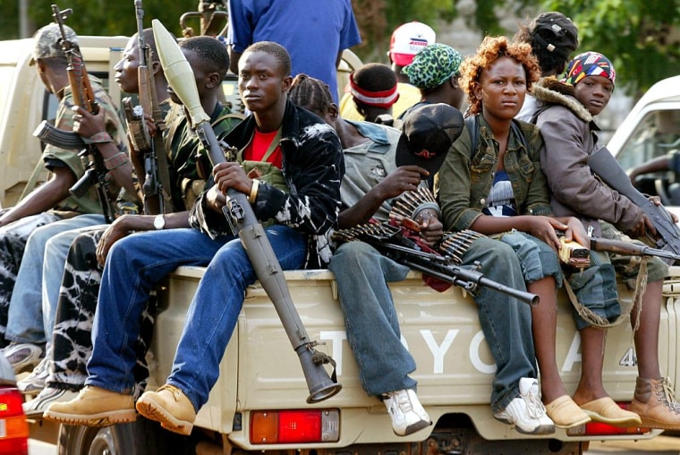 Una camioneta con jóvenes soldados leales al presidente liberiano Charles Taylor escolta el SUV blindado de Taylor durante un recorrido por la línea de defensa de Monrovia el 29 de junio de 2003.