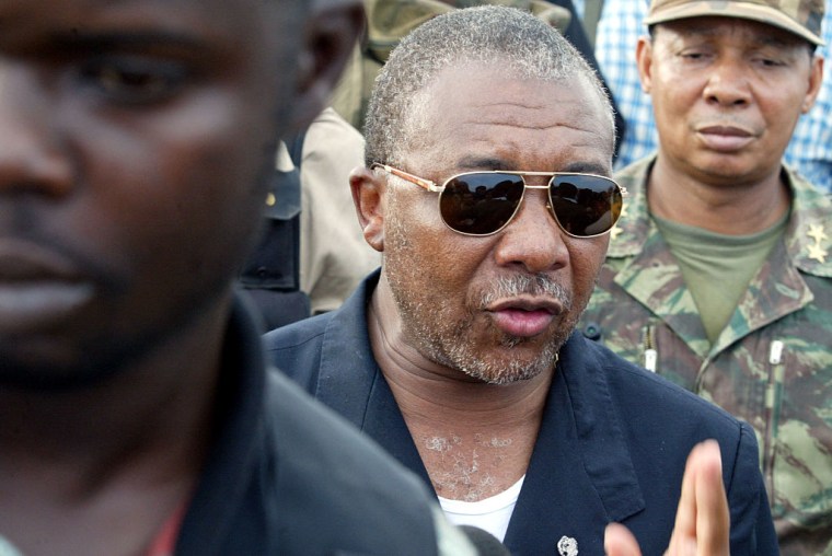 El entonces presidente de Liberia, Charles Taylor (a la der.), rodeado de guardaespaldas, visita las fortificaciones situadas a la entrada de Monrovia, custodiadas por el ejército, el 28 de junio de 2003. 