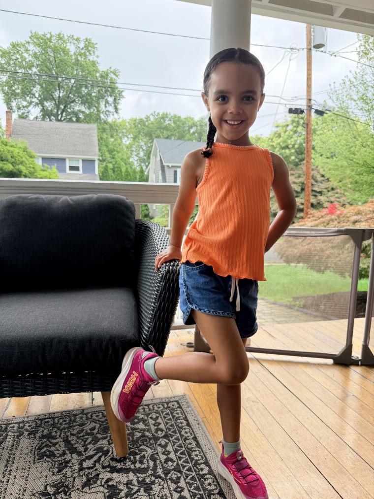 A little girl wearing Hoka sneakers for kids.